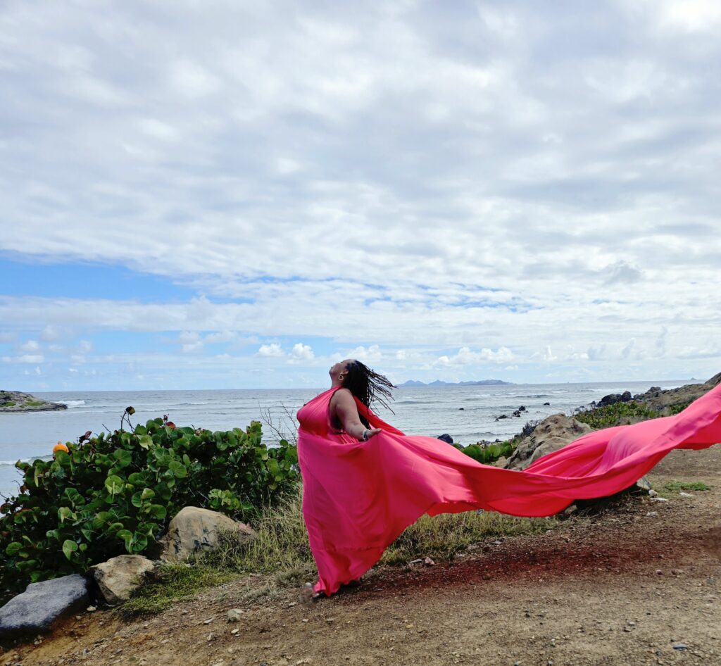 Hedreich in coral dress on rocky beach